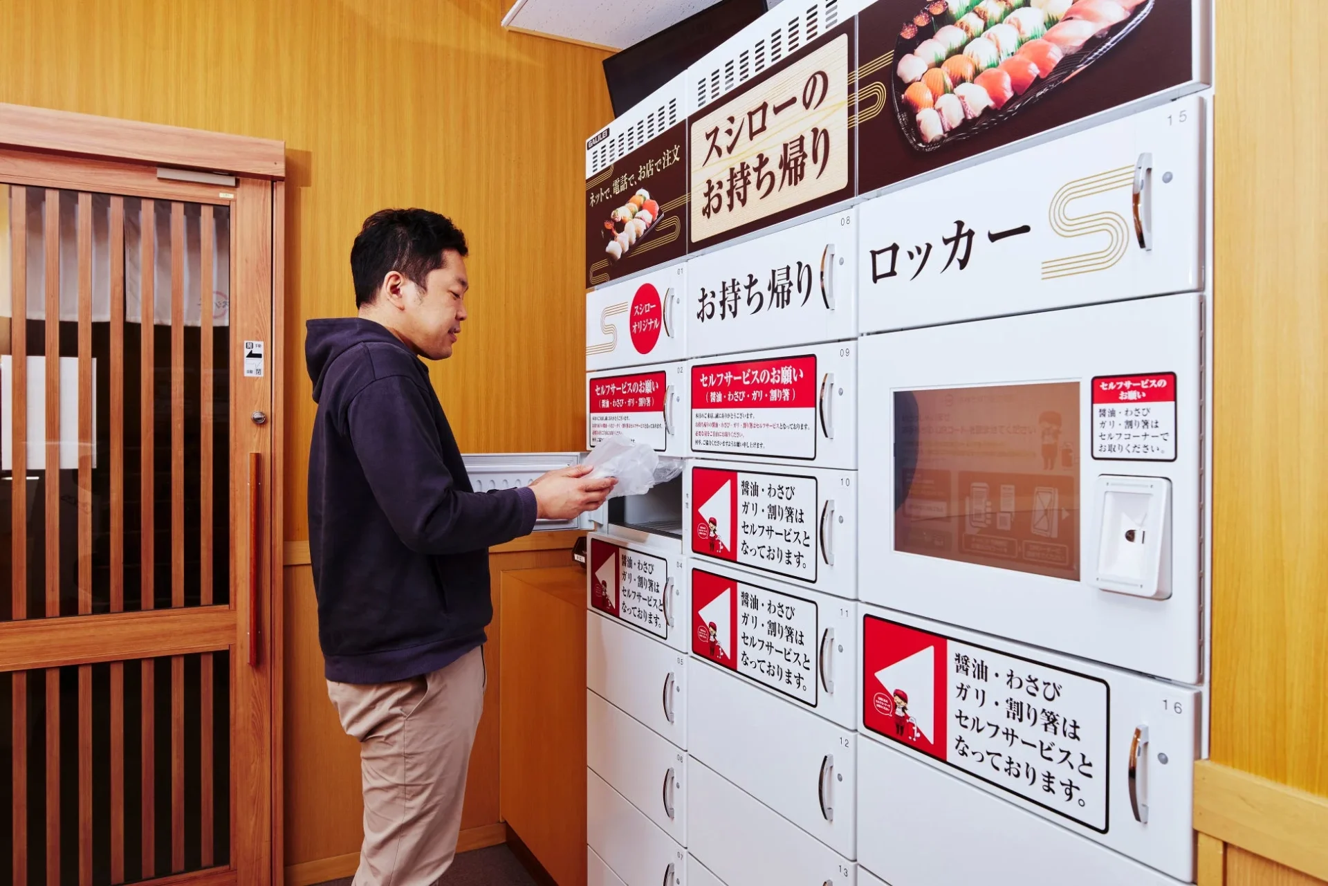 スシローの店舗に設置された自動土産ロッカーから商品を受け取る男性
