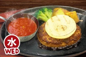 水曜日の日替り130gハンバーグ。ハンバーグの上に玉ねぎの輪切りグリルが乗り、トマトガーリックソースが添えられています。
