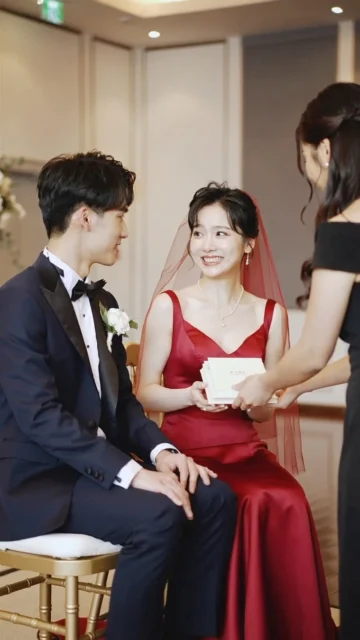 結婚式で新郎新婦が友人からお祝いの寄せ書きブックを受け取るシーン