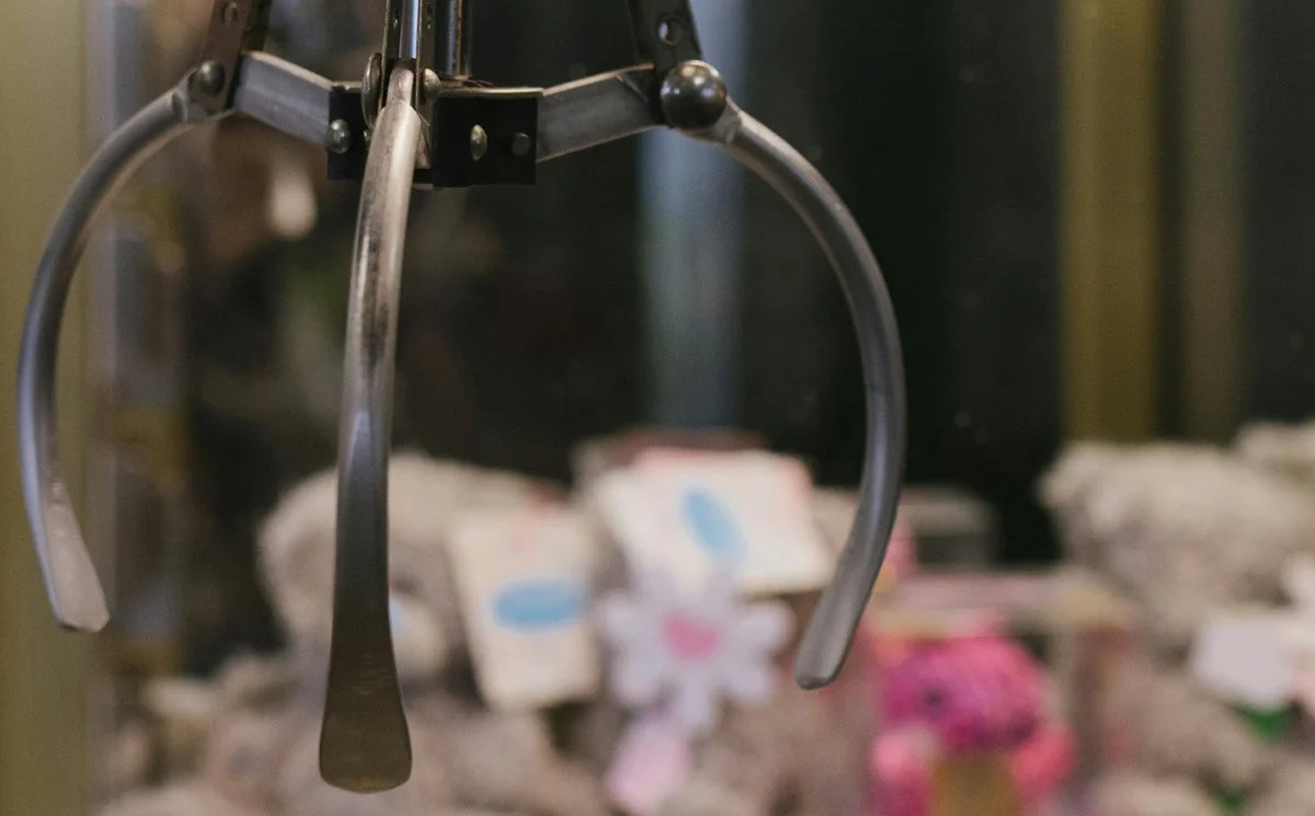 クレーンゲームの景品を掴むクレーンの爪のアップ