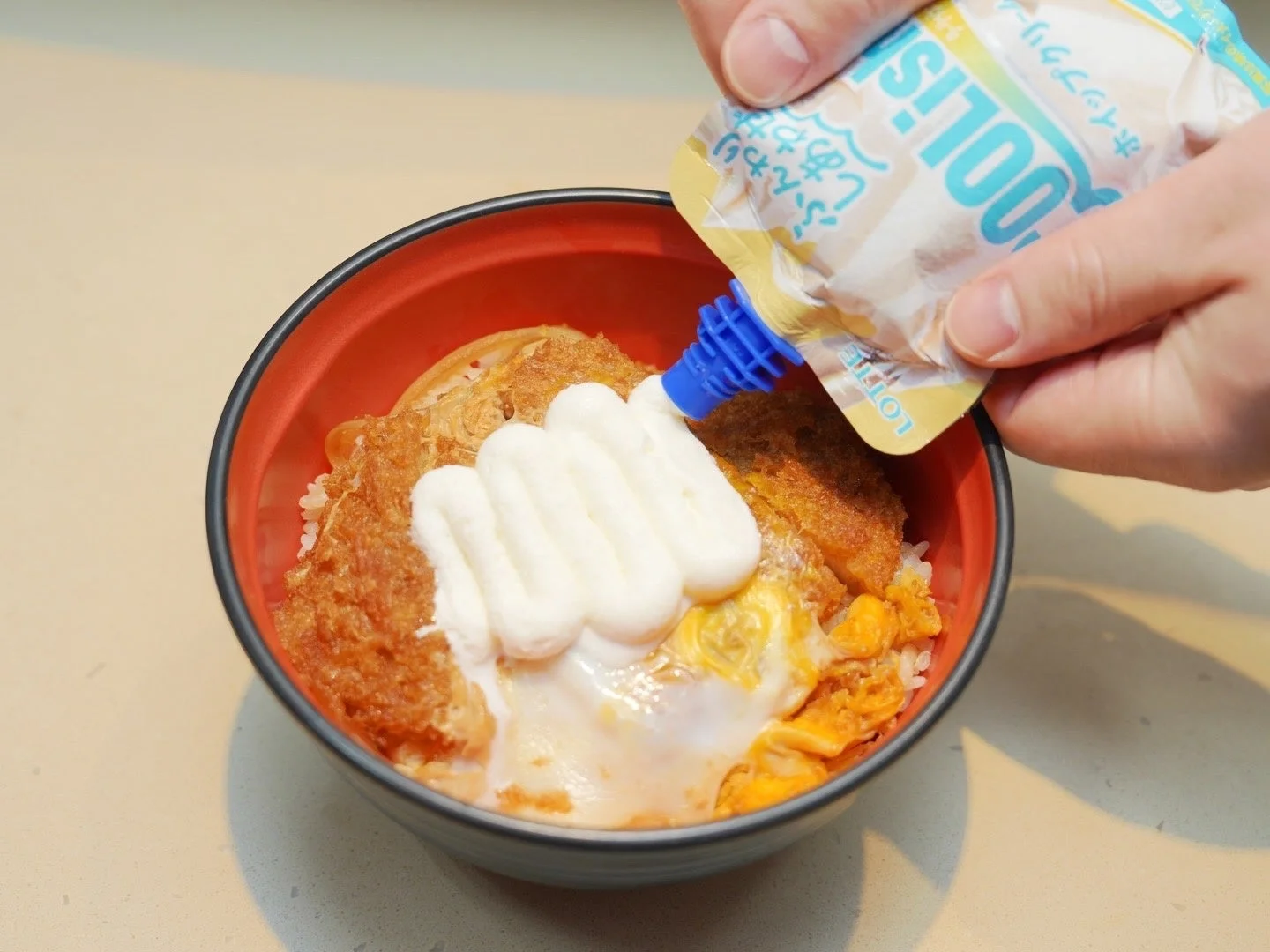 かつ丼に「クーリッシュ ホイップクリーム」をトッピングしている様子