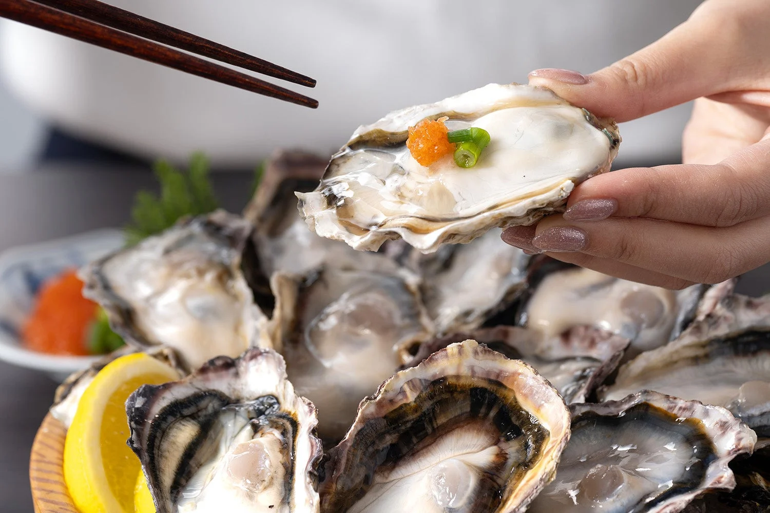 庄やで提供される新鮮な生牡蠣を箸でつまむ手元