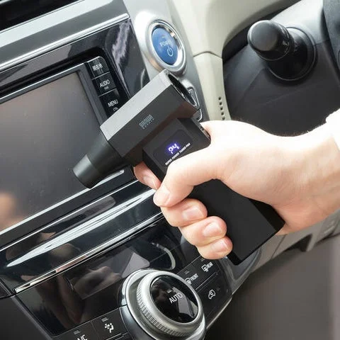 電動エアダスターで車内のエアコン吹き出し口を掃除する様子