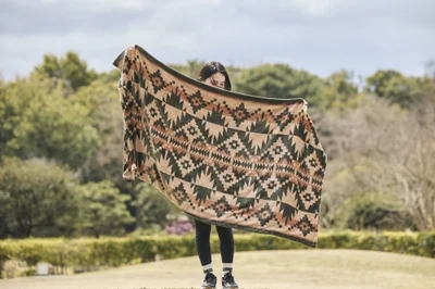 PowerArQの電気毛布を広げて持つ女性のアウトドアシーン