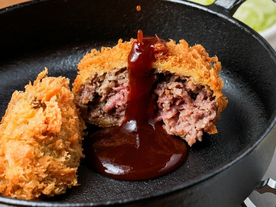 メンチカツに特製定番ソースをかける様子