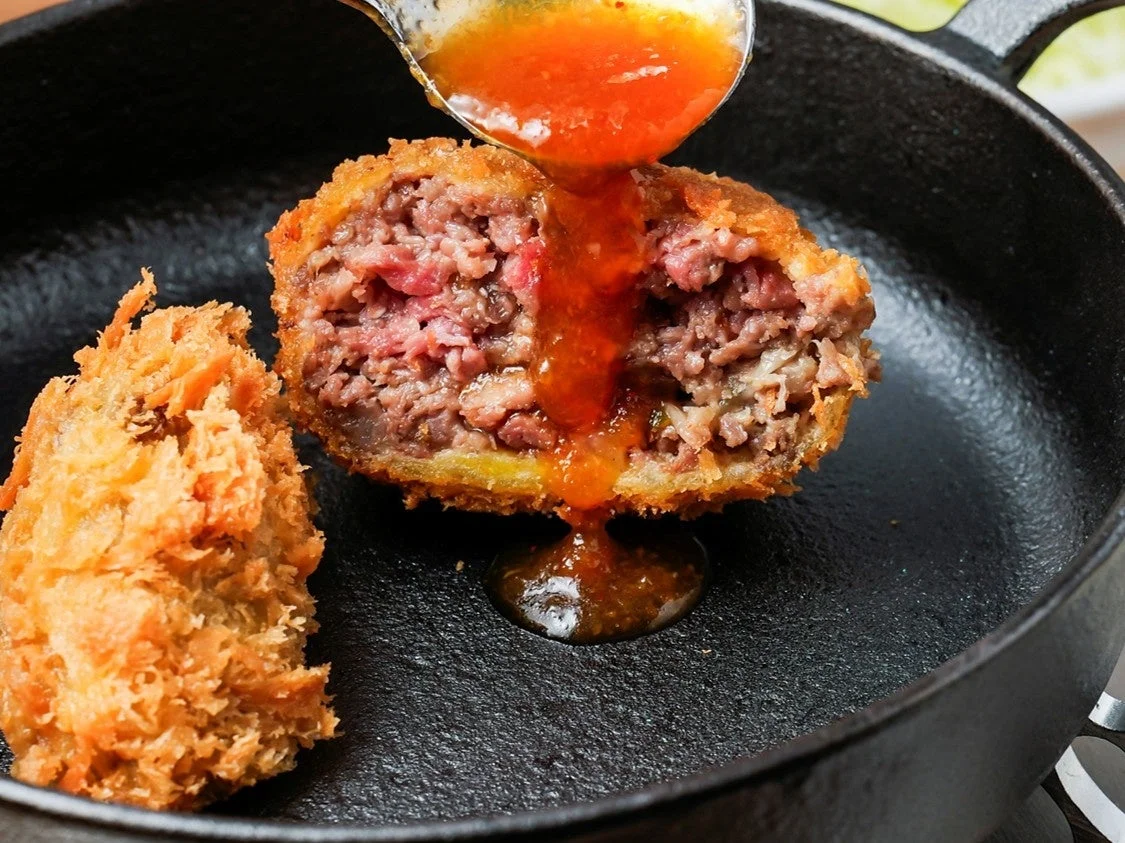 メンチカツにおろしポン酢をかける様子