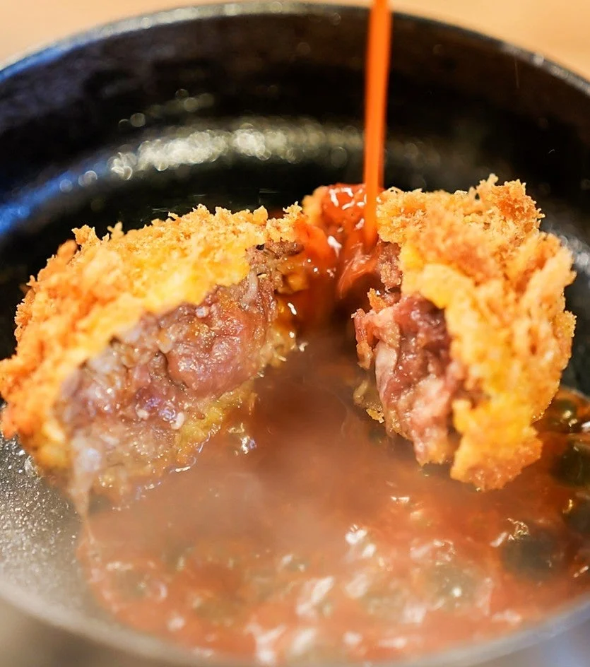 鉄板の上で自家製デミグラスソースをかけたメンチカツ