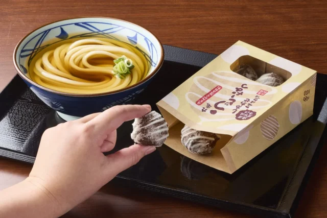 温かいうどんと「丸亀うどーなつ 濃厚ダブルチョコ しあわせミルク味」を一緒に楽しむ様子。