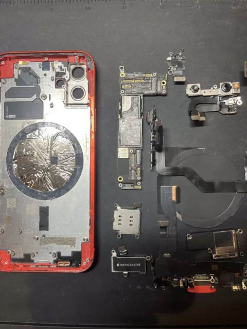 分解されたiPhoneの内部部品と基板、修理準備の様子