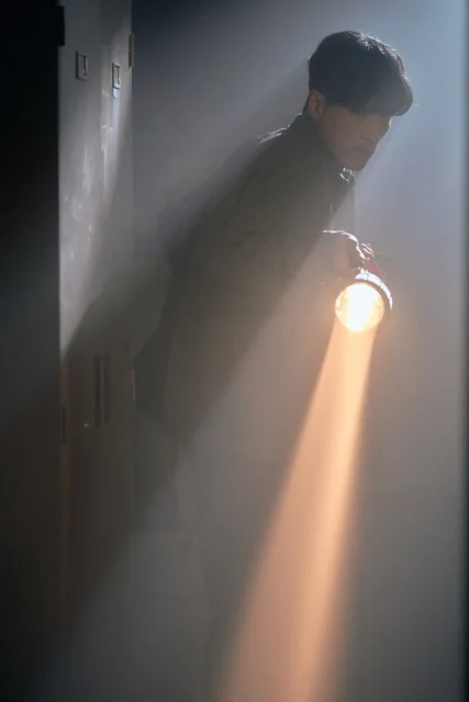 懐中電灯で暗闇を照らしながら進む鬼川治男（半田周平）