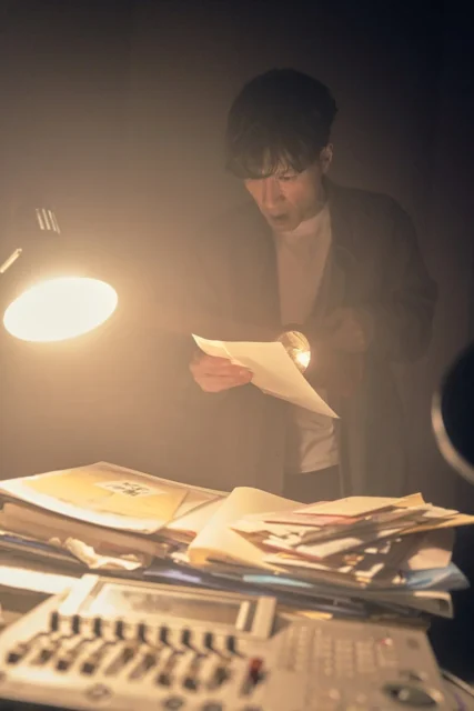 ラジオ局で書類を調べる鬼川治男（半田周平）