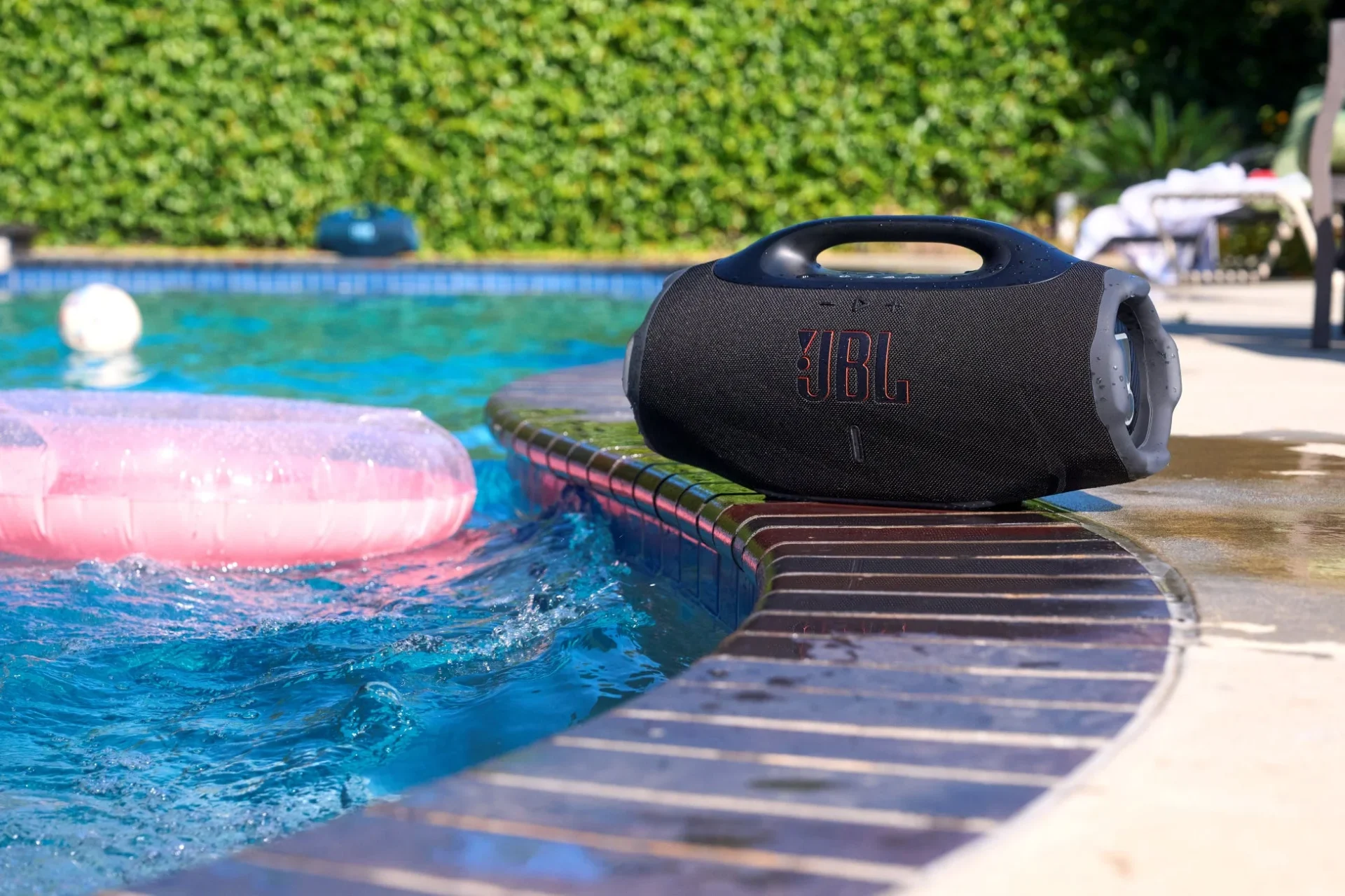 プールサイドに置かれたJBL Boombox 4。水しぶきが上がり、高い防水性能を示す使用シーン