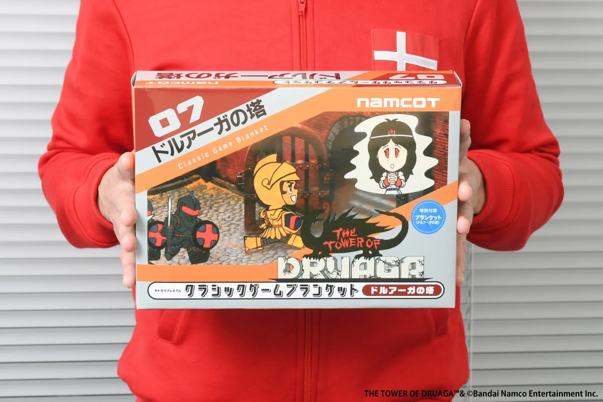 人物が持つクラシックゲームブランケット「ドルアーガの塔」のパッケージ