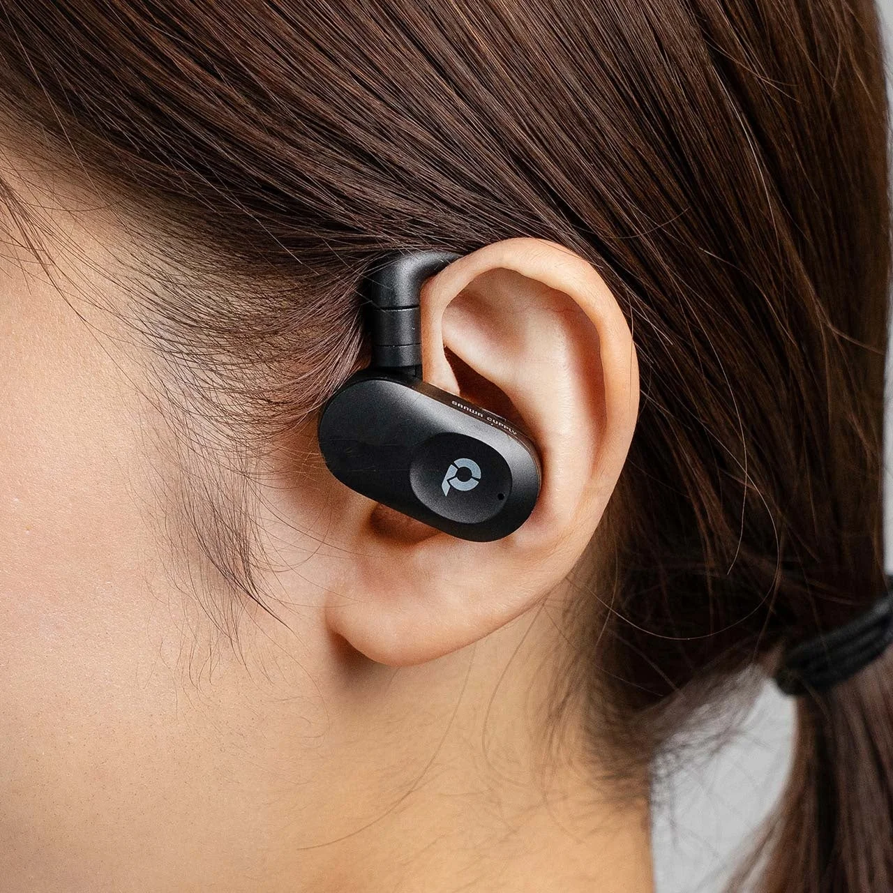 オープンイヤー型ワイヤレスイヤホンを装着した女性