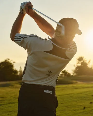 Metalwood Studioのポロシャツを着用してスイングするゴルファー