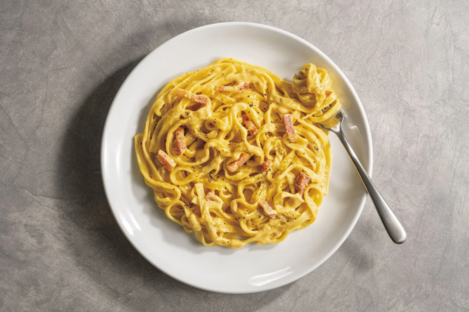 燻製パンチェッタが香る平打ち麺仕立ての濃厚カルボナーラ