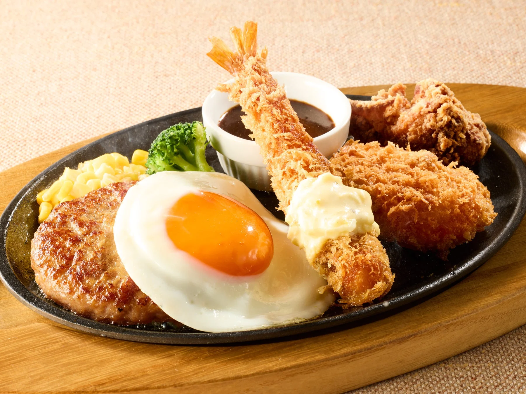 ココスの「満腹！オールスタープレート」。ハンバーグ、目玉焼き、海老フライ、カニクリームコロッケ、唐揚げが盛り合わせられた鉄板プレート。