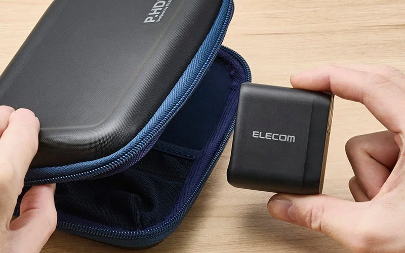 手のひらサイズのコンパクトなエレコムAC充電器をケースに収納する様子