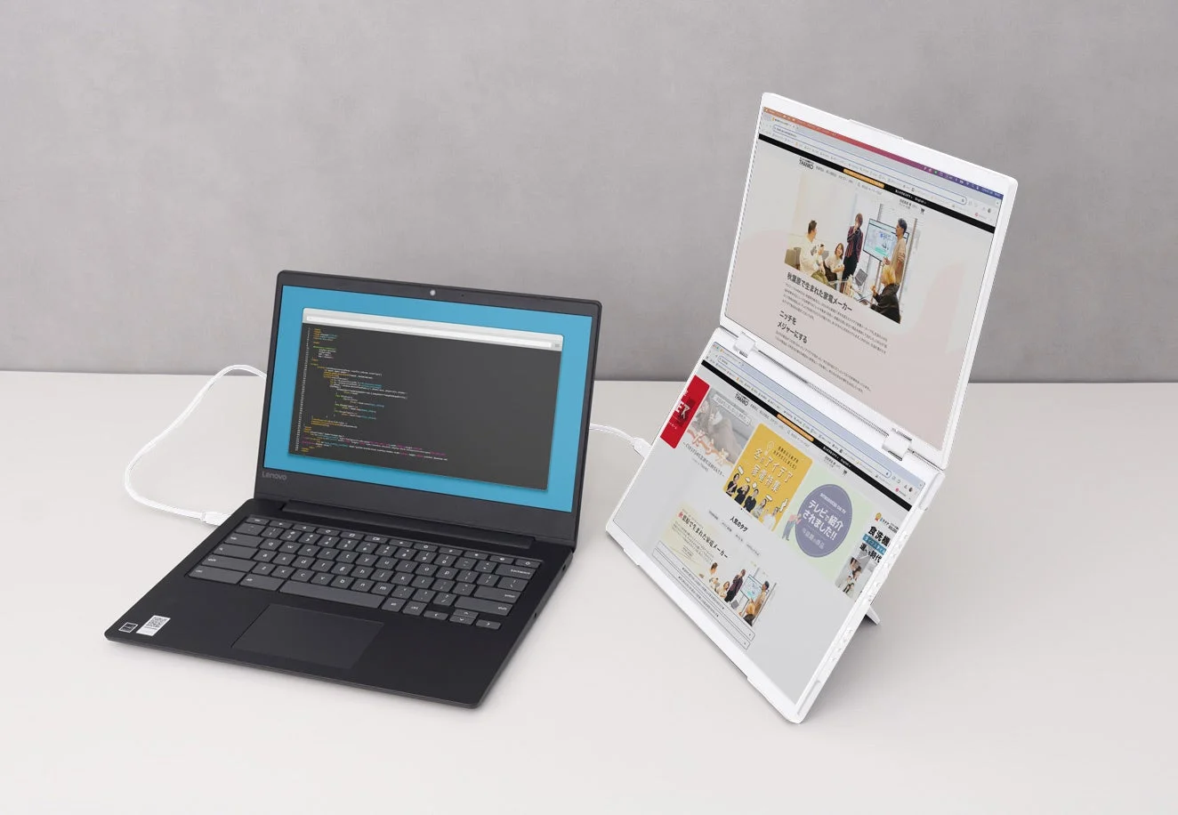 ノートPCに接続された上下2画面モニターでのウェブサイトとコード表示