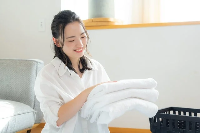 畳まれたふわふわのタオルを笑顔で抱える女性
