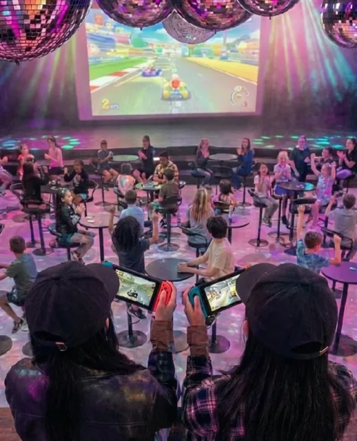 大画面に映るマリオカートを見つめ、コントローラーを操作する参加者