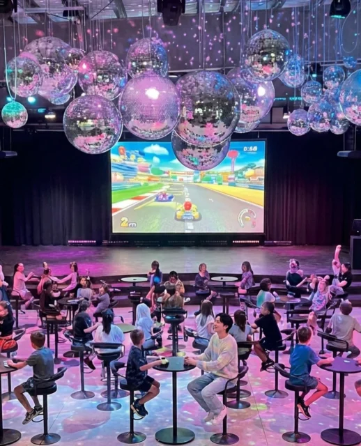 WHATAWONのFloor Disco Ball会場でマリオカートを楽しむ人々