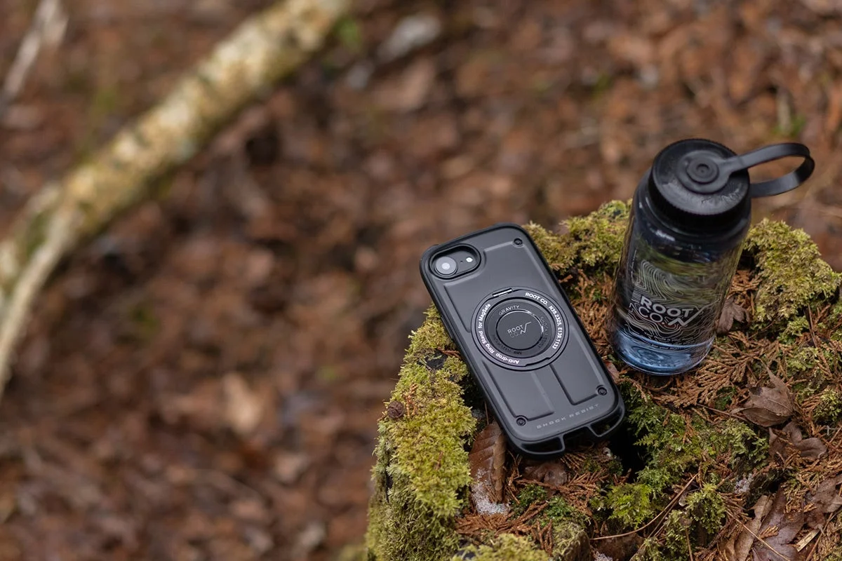 自然の中でROOT CO.のiPhoneケースとボトルを置いたイメージ