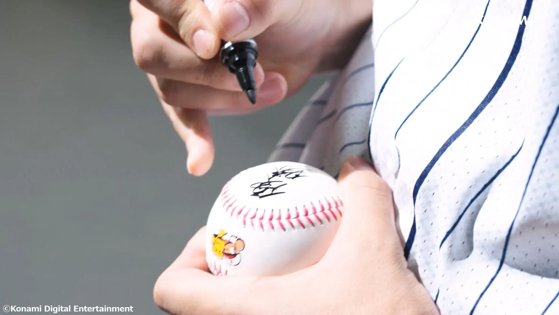 大谷翔平選手が野球ボールに力強くサインを書き込む様子。