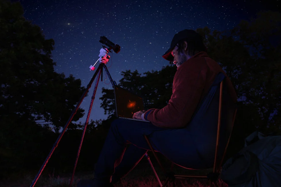 星空の下でMacBook Proを使用するユーザー、長時間のバッテリー駆動を表現