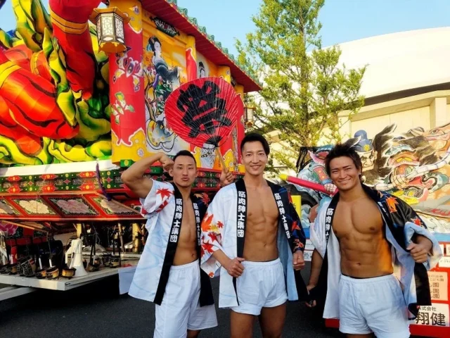 筋肉紳士集団ALLOUTによる「筋肉盆踊り」の様子。和装のマッチョたちが祭りの山車を背景にポーズ。