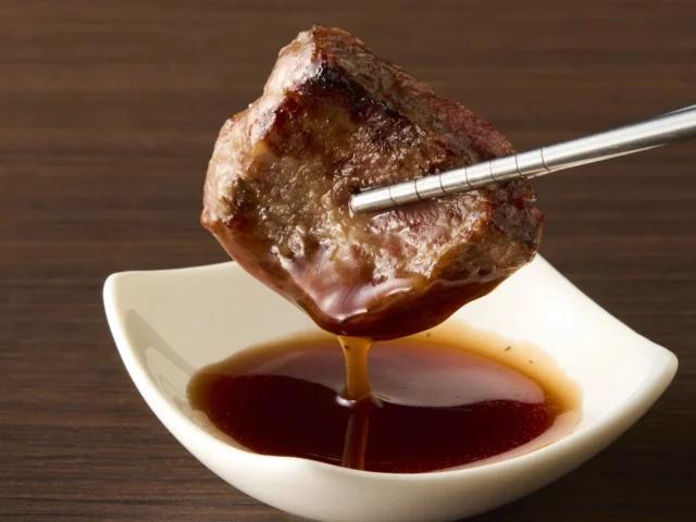 焼き上げた「厳選上みすじ」をトリュフ香る赤ワインソースにつける様子