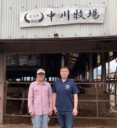 中川牧場前にて、大宮牛肉店代表の寺出さんと中川畜産8代目中川正成さん。