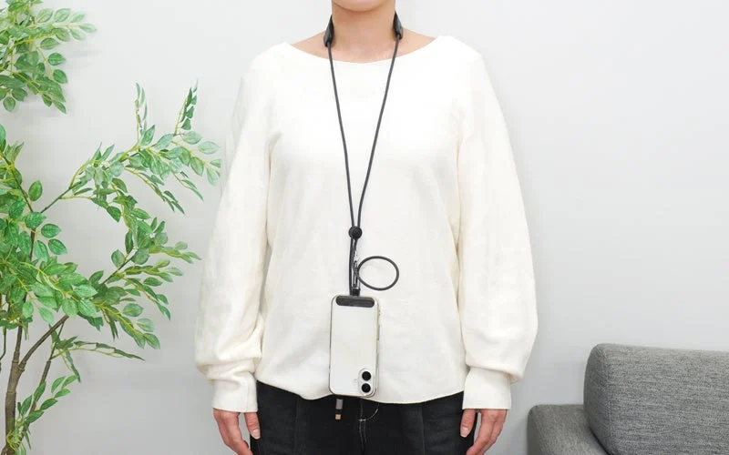 「3in1スマホショルダーケーブル」を首にかけてスマホを使用する女性