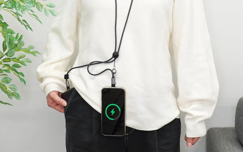 「3in1スマホショルダーケーブル」でポケットのモバイルバッテリーからスマホを充電する女性
