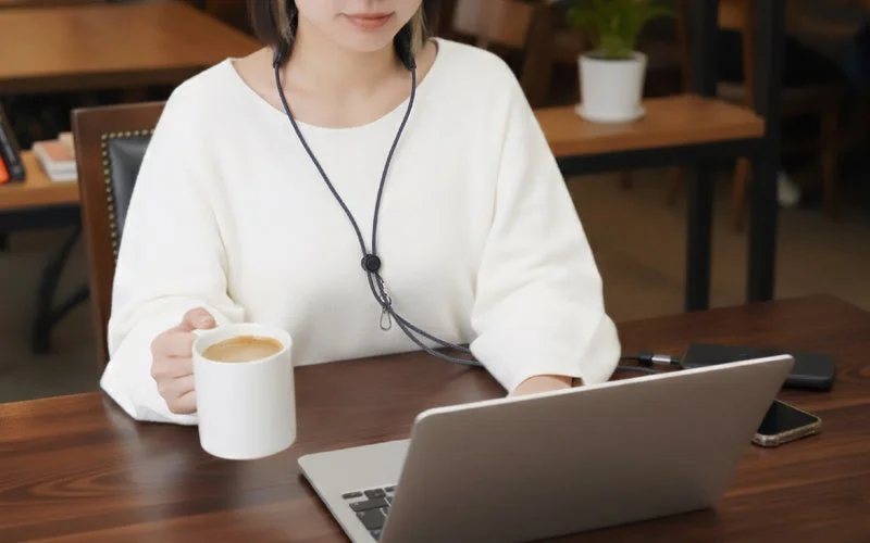 「3in1スマホショルダーケーブル」を着用してPC作業中に首をリフレッシュする女性