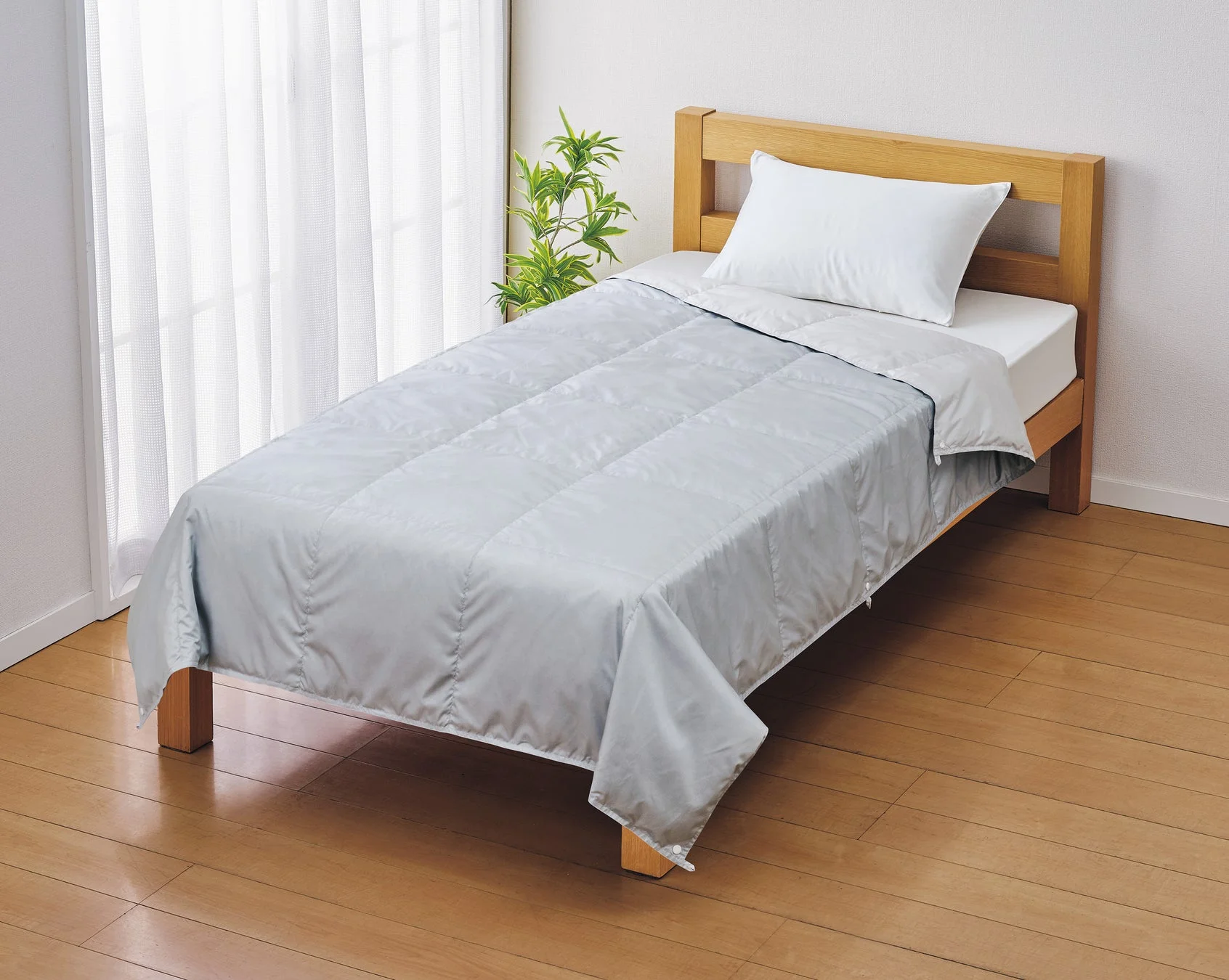 ホームコーディの洗える羽毛肌掛ふとんがシングルベッドにかけられている様子。