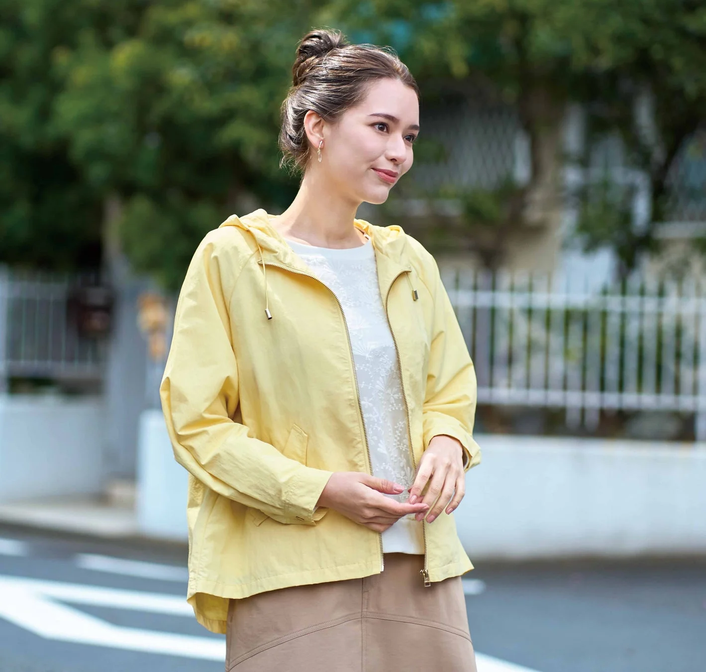 黄色い花粉対策カラフルマンパーを着用し、屋外で笑顔を見せる女性。