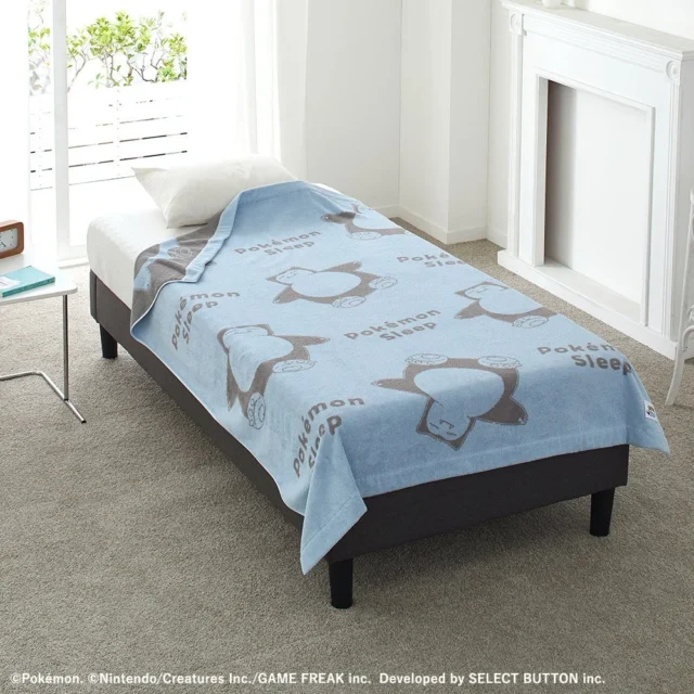 ベッドに広げられたカビゴン柄のブルーのタオルケット。