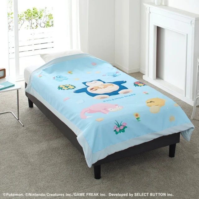 ベッドに広げられたシアンの砂浜デザインのブルーのリバーシブルキルトケット。