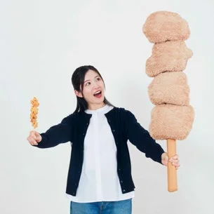 女性が特大からあげ棒ぬいぐるみを持つ様子