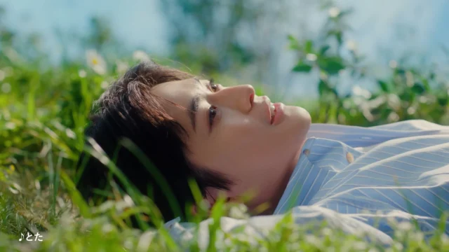 草原に寝そべり空を見上げる高橋文哉さんの横顔