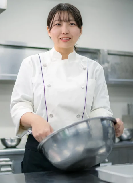 スシローカフェのパティシエ佐藤真衣子さんが笑顔でボウルを持っている様子