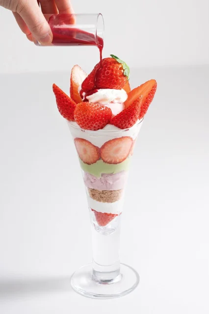 あまおう苺のパフェに甘酸っぱいフランボワーズソースをかける様子