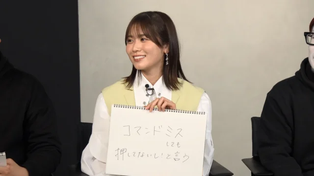 丹生明里さんが「コマンドミスしても押してない！と言う」と書かれたフリップを見せる