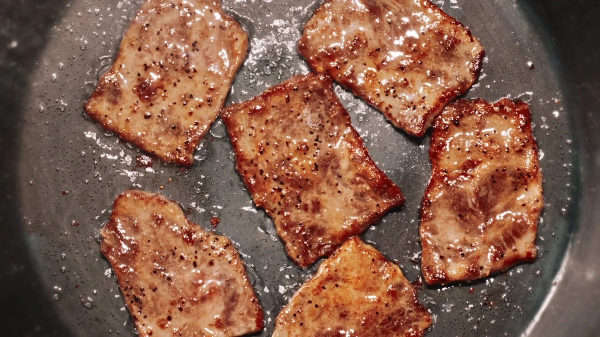 ほっともっと「新・ビーフカットステーキ重」のステーキ肉を焼くシズル