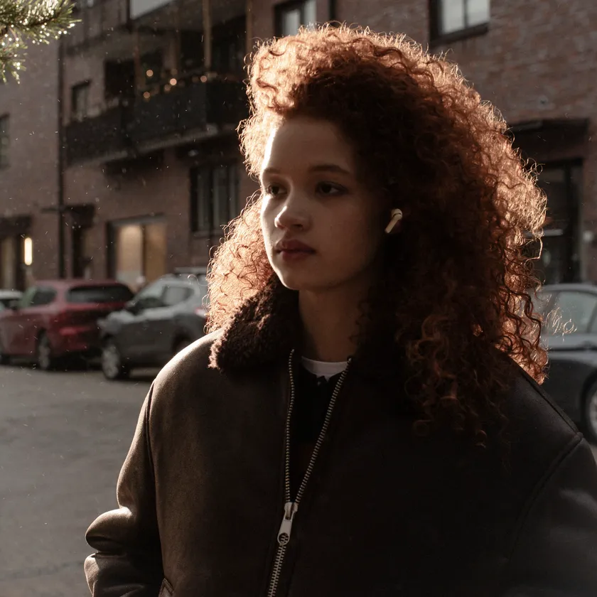 Sudio E4 Pro クラウディホワイトイヤホンを着用し屋外で過ごす女性