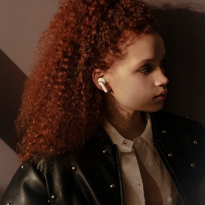 Sudio E4 Pro クラウディホワイトイヤホンを着用し室内でリラックスする女性