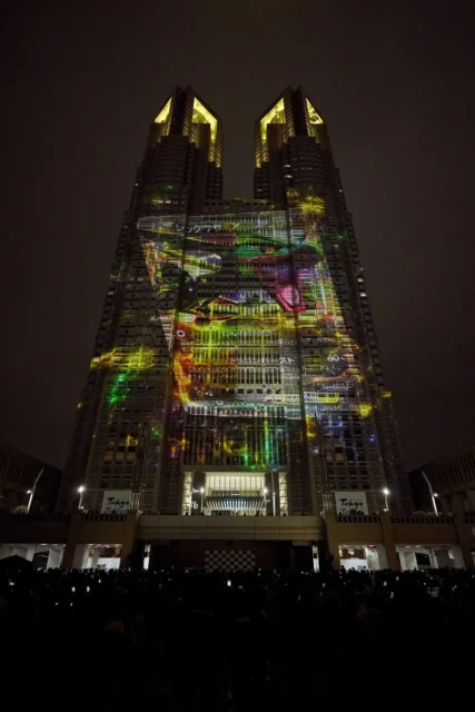 都庁に映し出されたリザードンを思わせるポケモンのプロジェクションマッピング