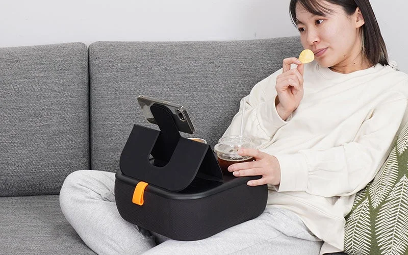 膝上テーブルクッション（ブラック）でくつろぎながらポテトチップスを食べる女性