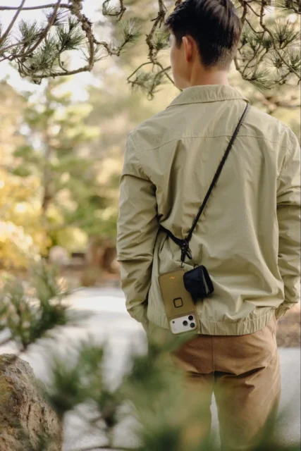 モバイル クロスボディ マルチストラップを装着して歩く男性の背面